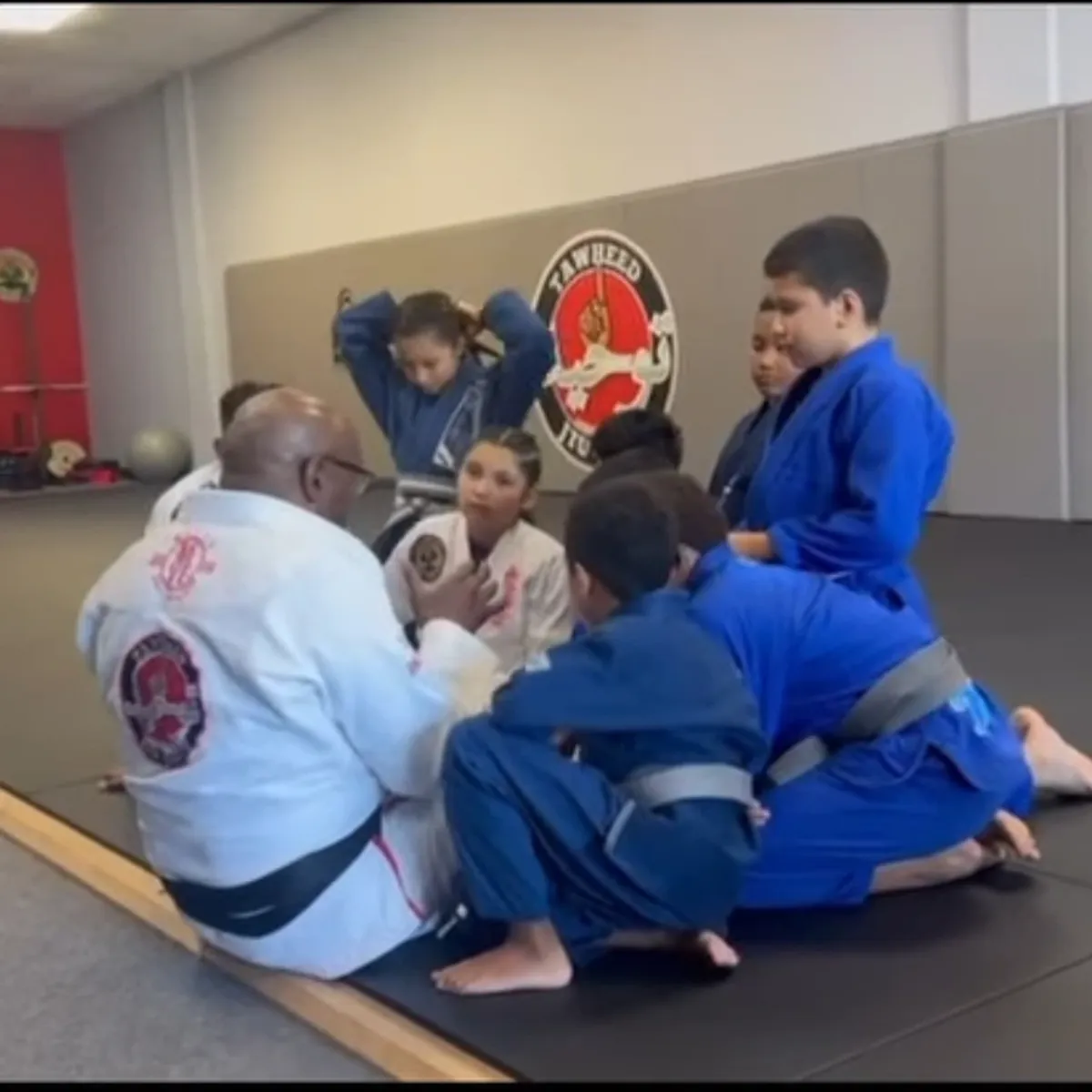 Coach teaching kids on the mats